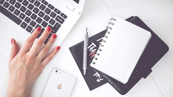 photo of a women at a laptop with a notebook